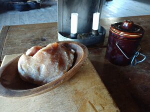 salt pork on a table beside a candle and a crock of butter