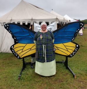 Allyson in a medieval dress, standing in front of butterfly wings.