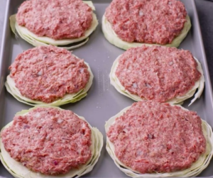 hamburger patties on slices of cabbage