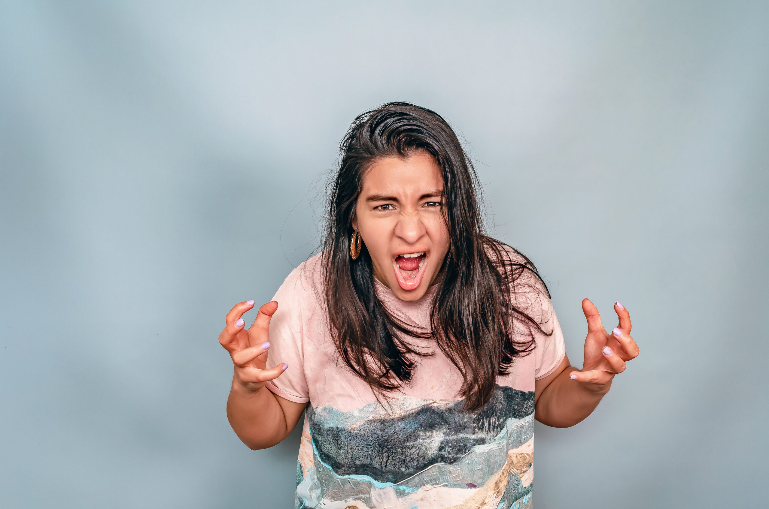 Angry woman screams. Latin American woman emotionally shows her anger with gestures.