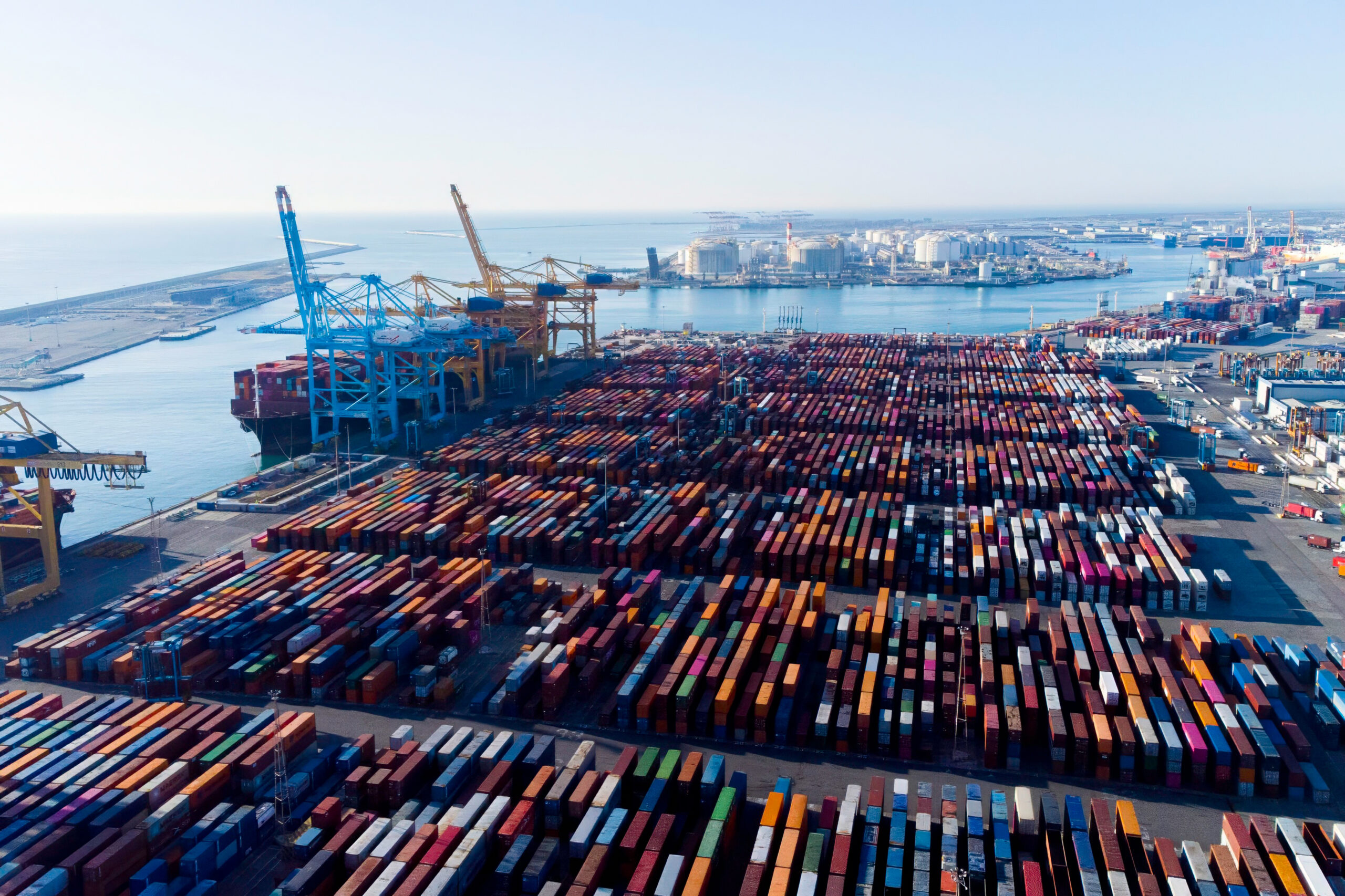 Aerial view of shipping containers and cargo ships in the sea port of Barcelona in Spain, Europe. Concept of sea and maritime trade and trade war due to tariffs. Commercial hub