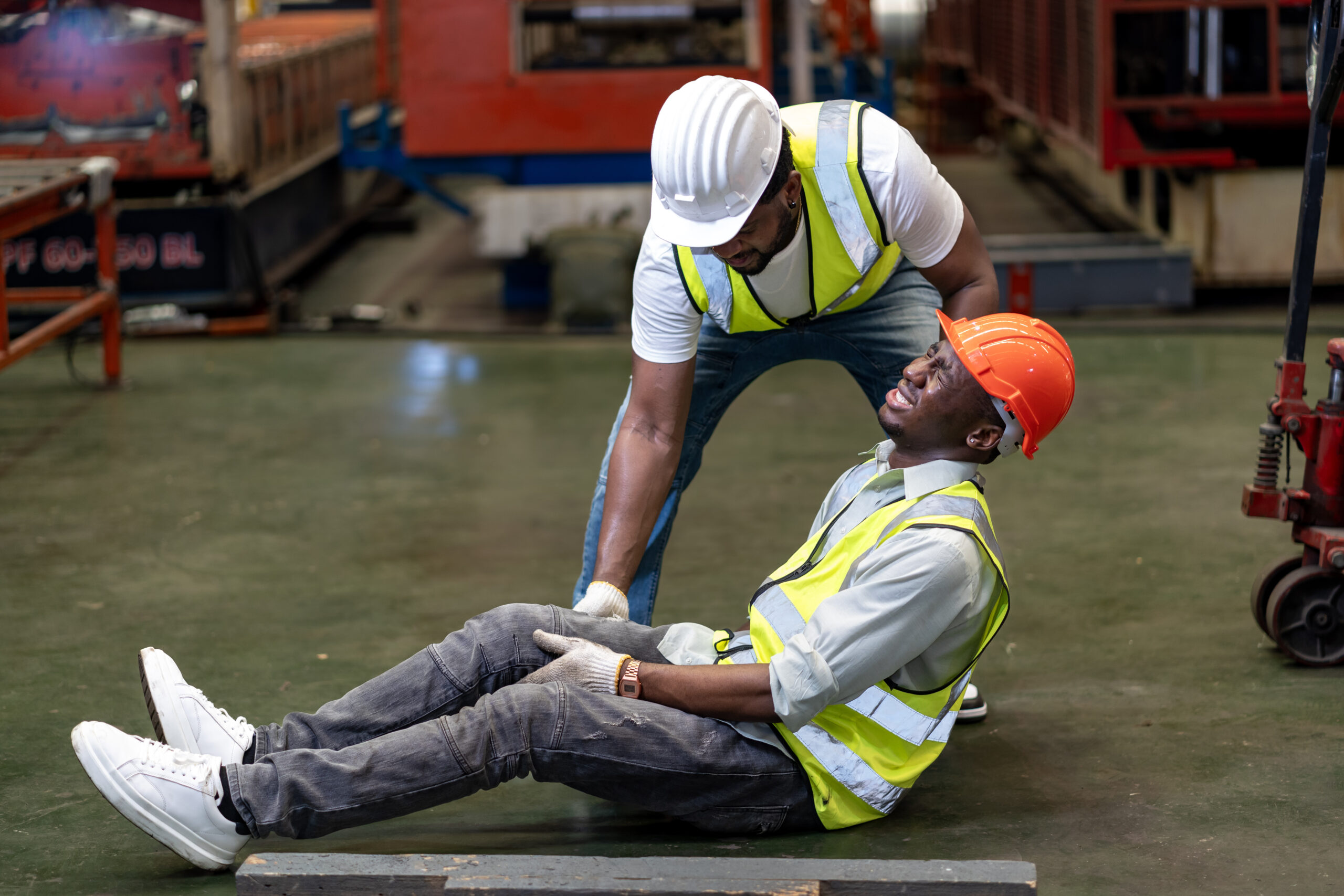 African American factory worker having an accident while working in manufacturing site while his colleague is helping  for safety workplace and emergency