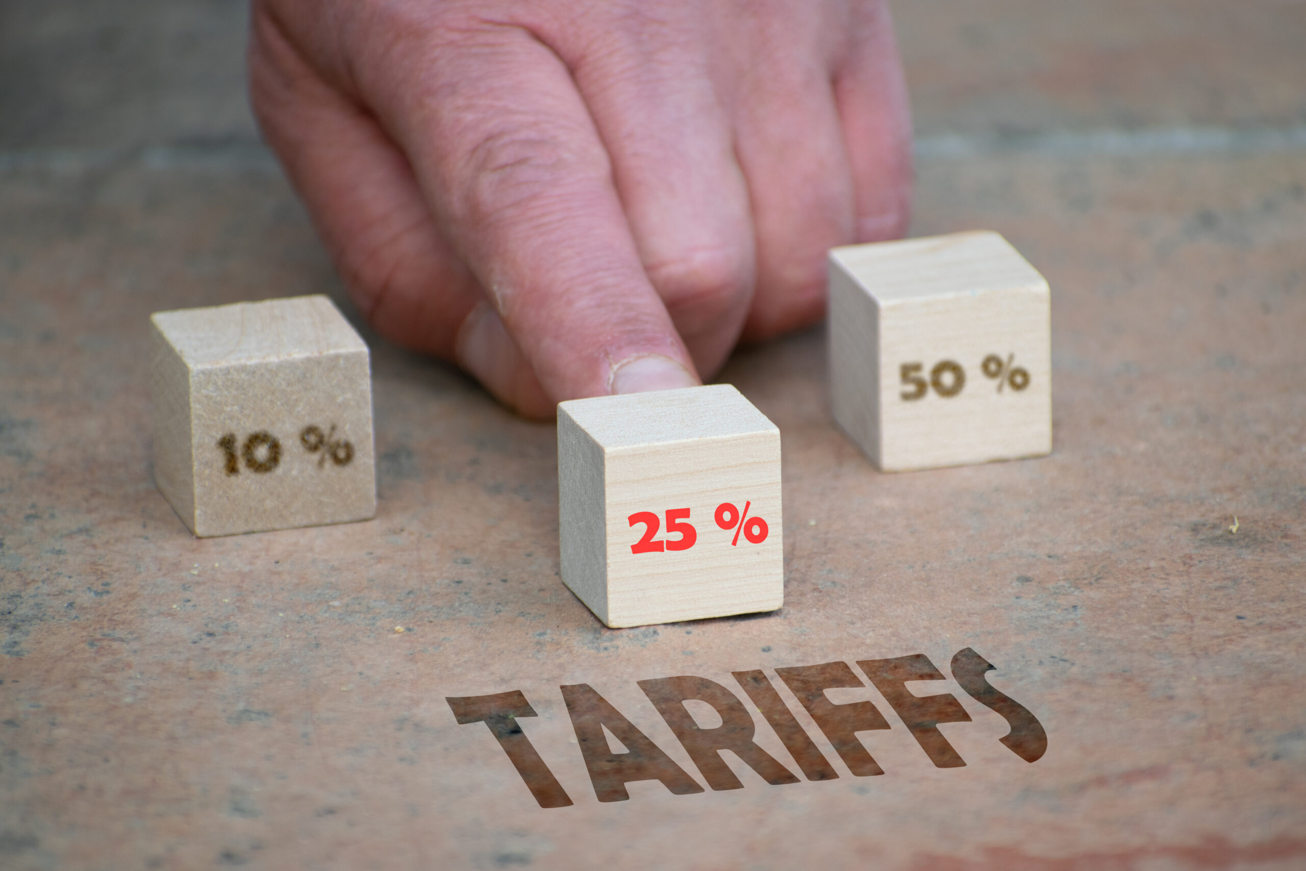 Concept illustrating the increase of tariffs. Three dices with 10 %, 25 % and 50 $. Focus is made on 25 %, the rest is purposely blurred