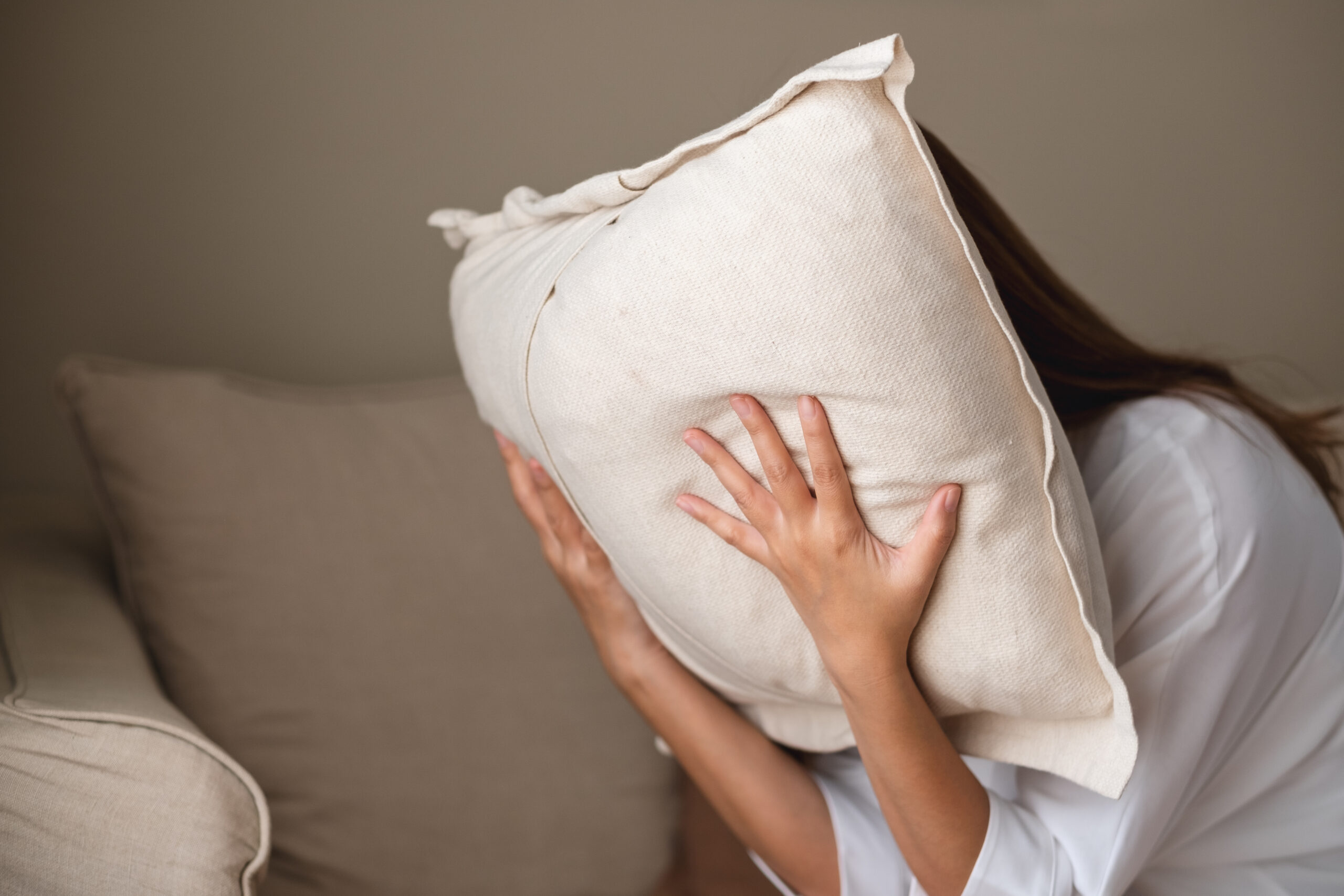 A depressed, stressed woman putting her face on a pillow, mental problem and health care concept