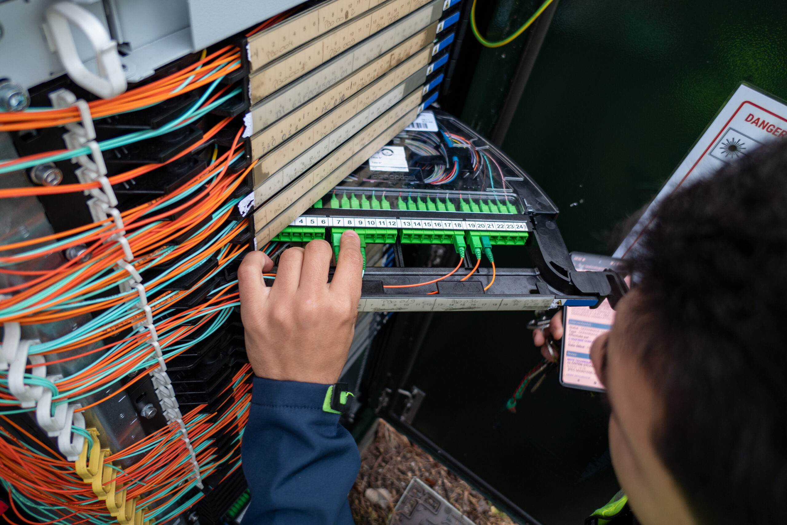 Fiber optic technician performs repairs on cabinet to restore network connection to customers impacted by failure