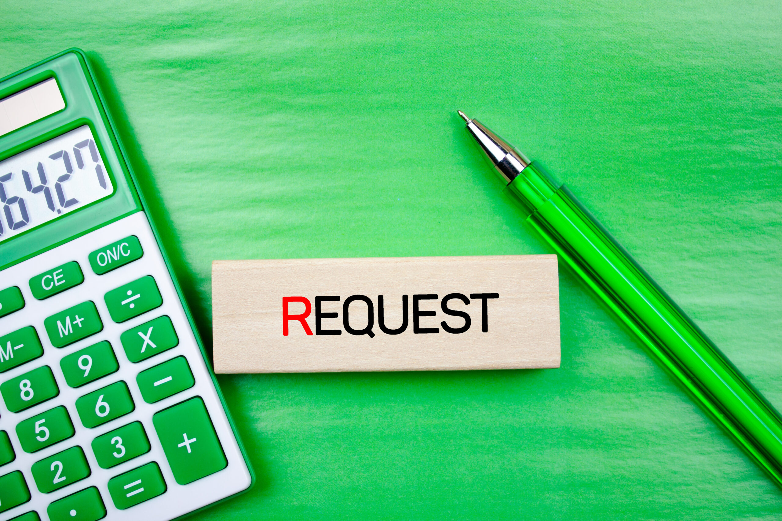Request word, text on a wooden block next to a calculator and pen. Request concept.