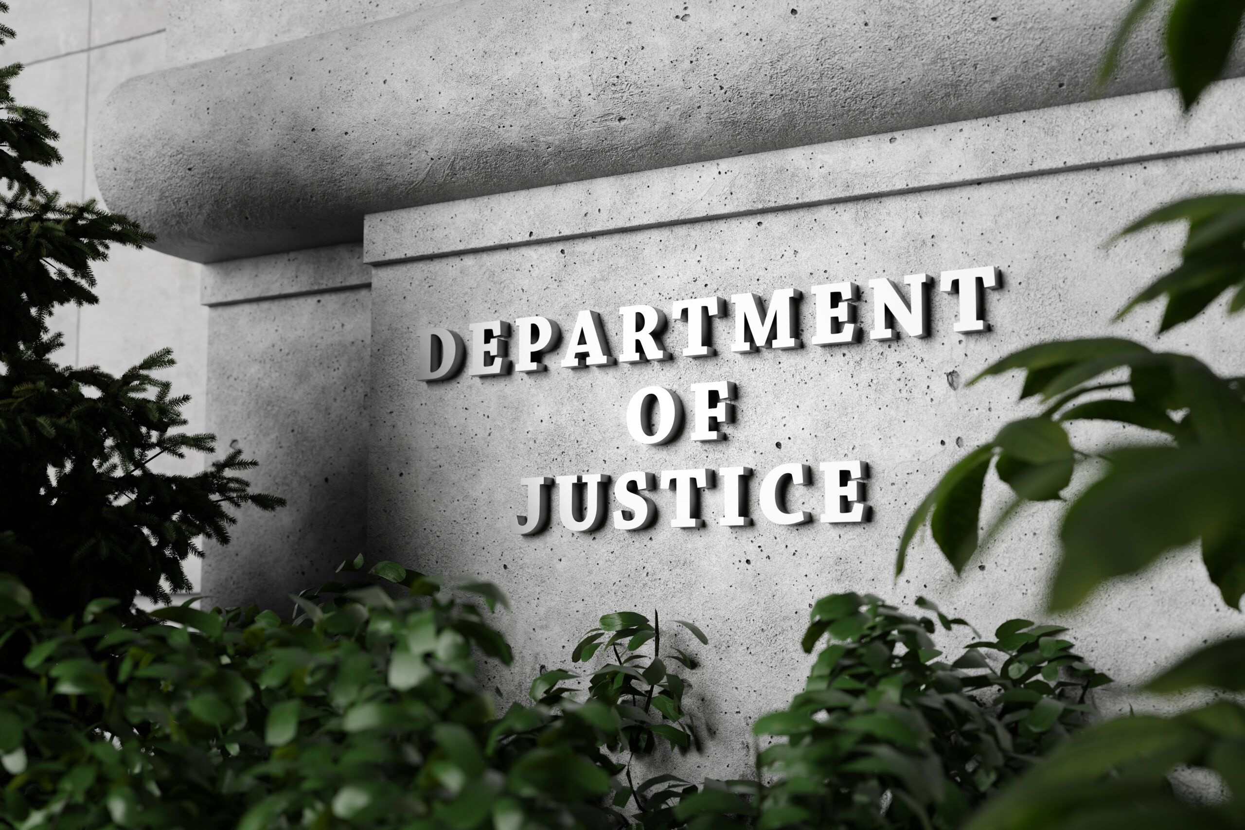 Silver sign of Department of Justice on a classical concrete wall with plants as foreground. Illustration of the concept of enforcement of federal laws