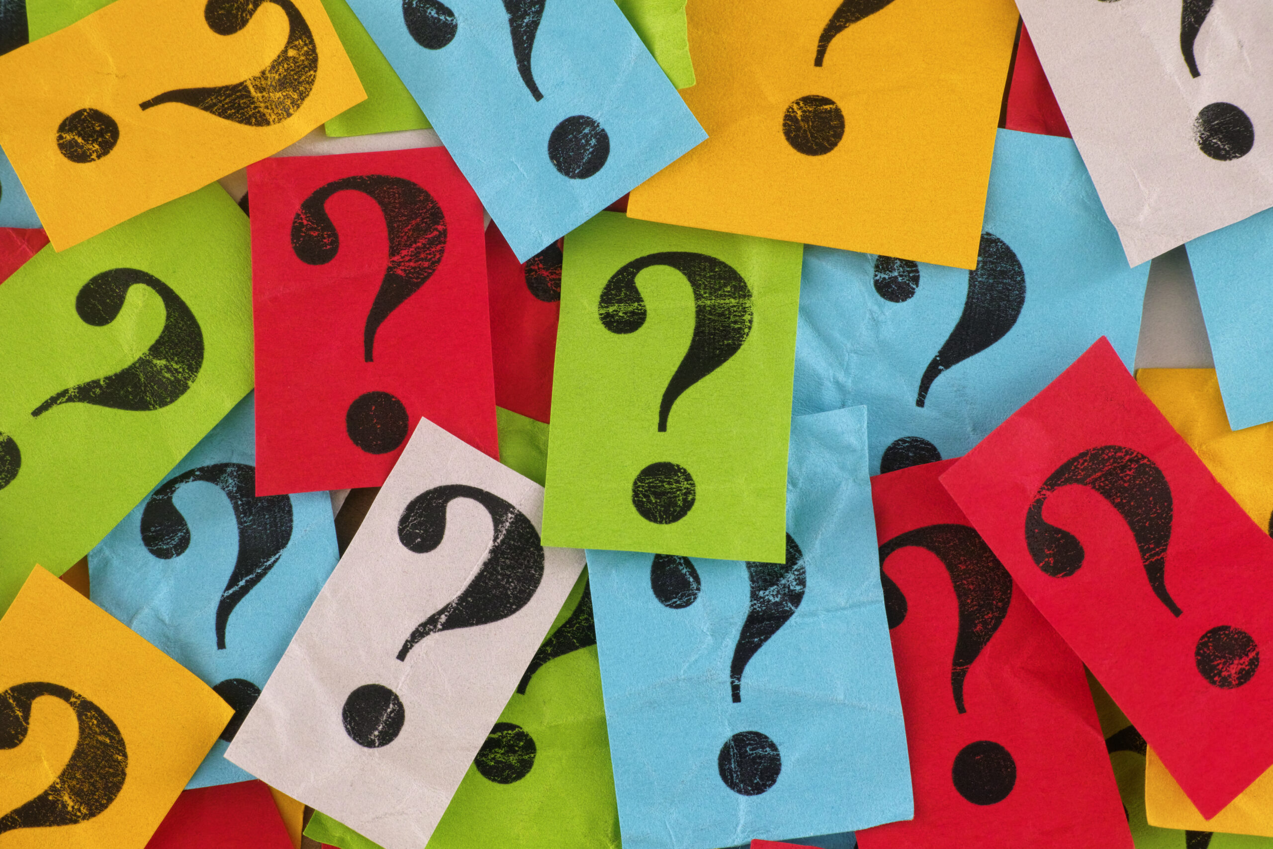 Too Many Questions. A pile of colorful paper notes with question marks on them. Close up.