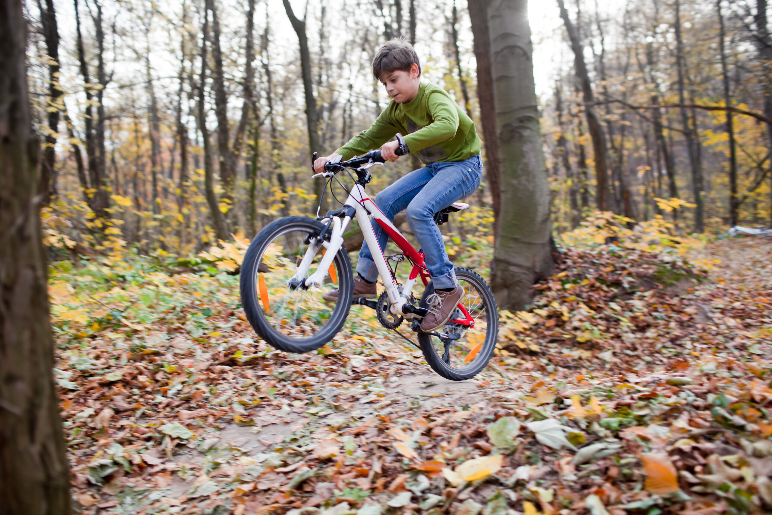 Boy riding a bike through a forest