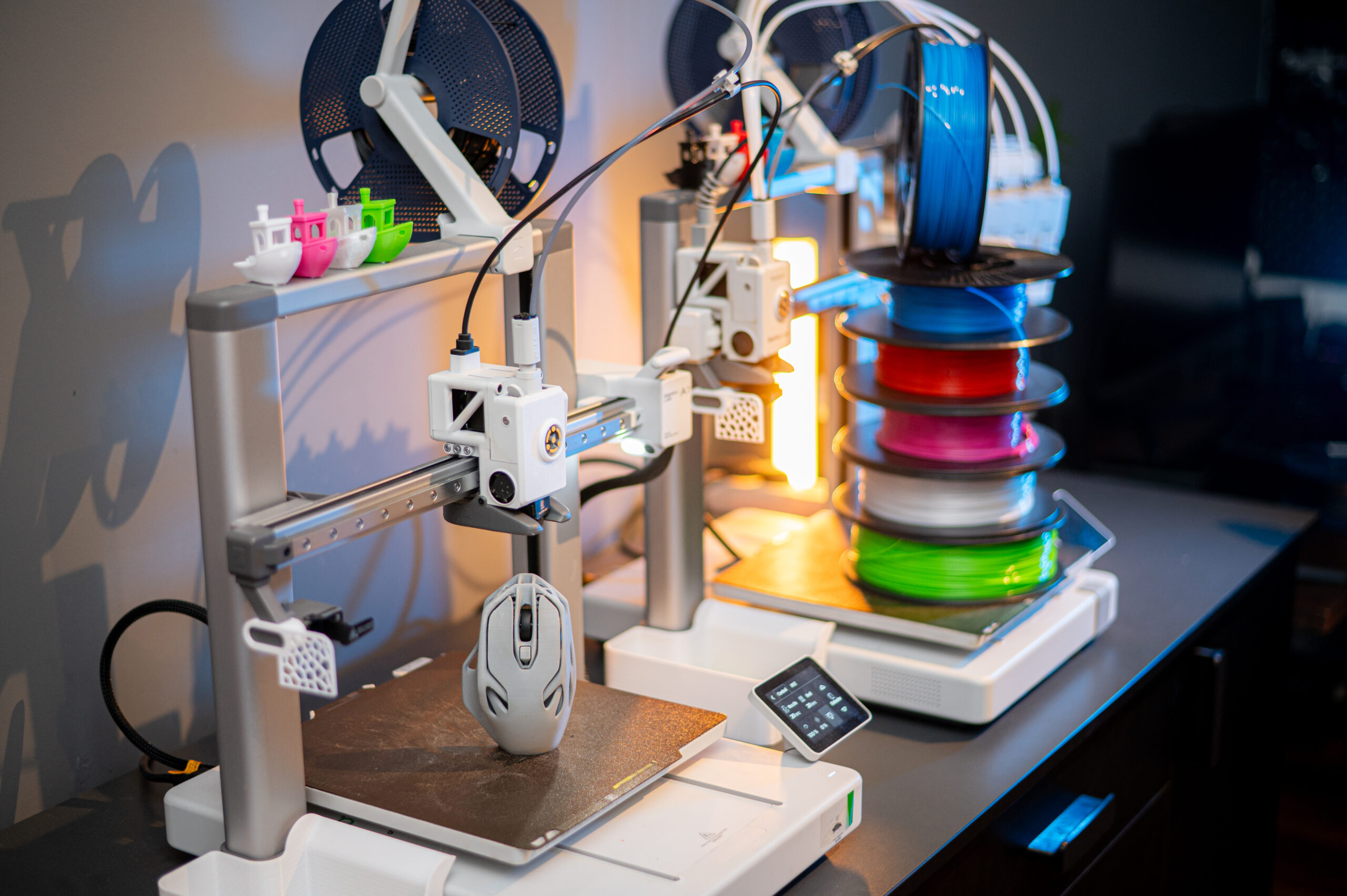 Modern Bambu Lab 3D printers with a stack of colorful filament spools and printed